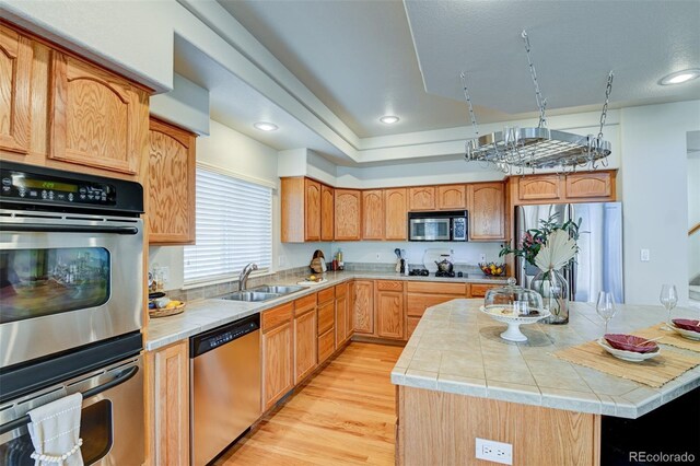 kitchen with sink, a kitchen island, stainless steel appliances, and light wood-type flooring