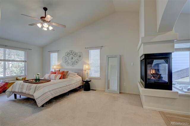 carpeted bedroom featuring ceiling fan, a multi sided fireplace, and high vaulted ceiling