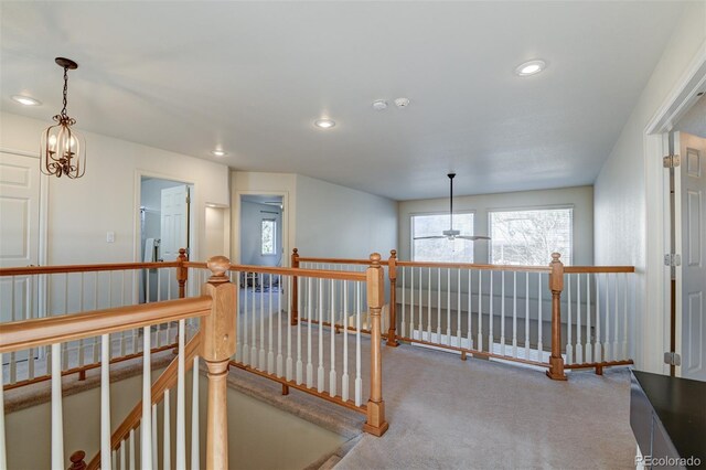 hallway with carpet and an inviting chandelier