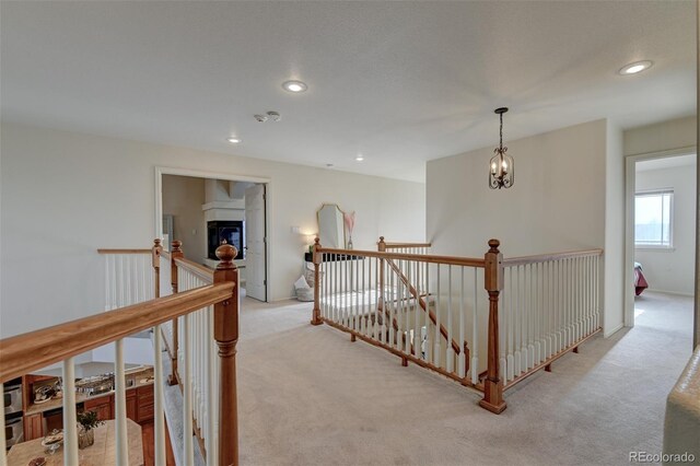 hall featuring light carpet and a chandelier