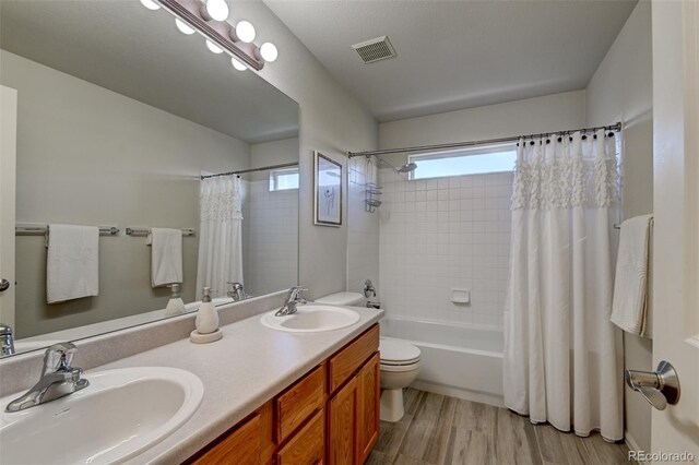 full bathroom with vanity, toilet, wood-type flooring, and shower / tub combo with curtain