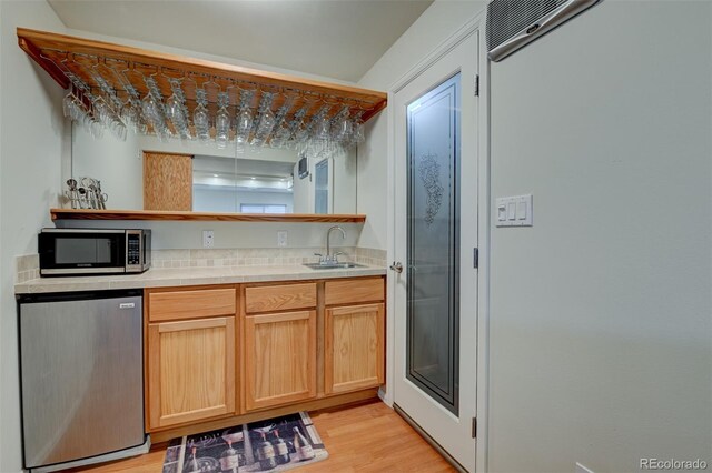 kitchen with light wood-type flooring, sink, light brown cabinetry, and fridge