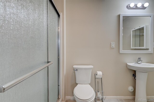 bathroom featuring toilet, walk in shower, and sink