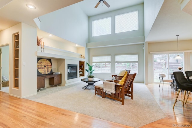 1460 Lily Lake Dr, Colorado Springs, CO 80921 - living room with ceiling fan, a glass covered fireplace, built in shelves, wood finished floors, and a towering ceiling
