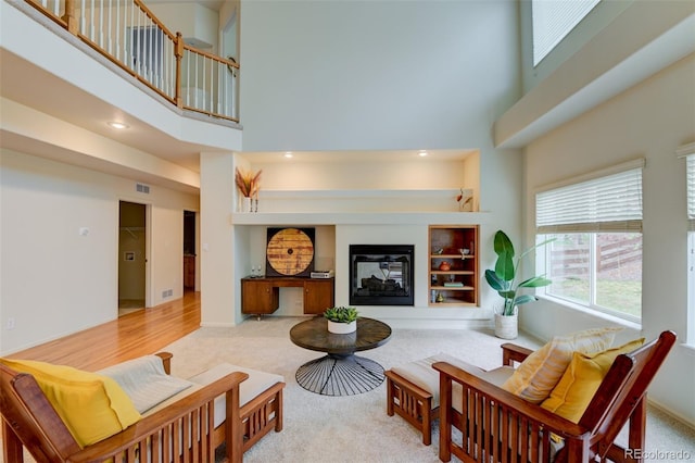1460 Lily Lake Dr, Colorado Springs, CO 80921 - living room featuring a multi sided fireplace, visible vents, built in features, a high ceiling, and carpet flooring