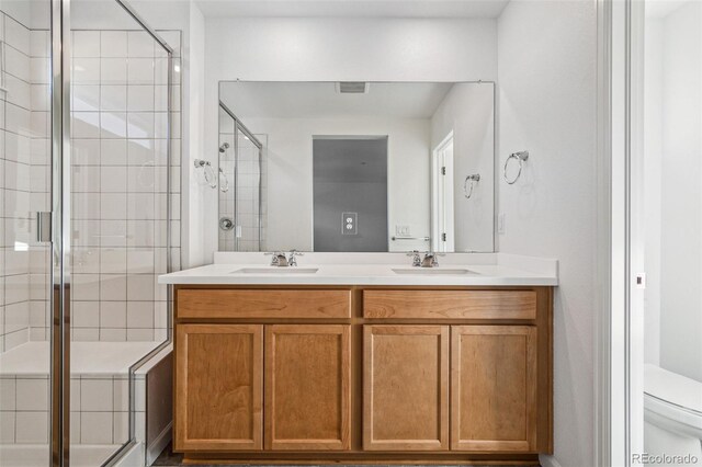 bathroom with vanity, a shower with shower door, and toilet