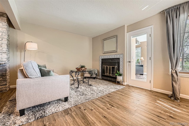 13704 E Lehigh Ave Unit D, Aurora, CO 80014 - living area with a fireplace, wood finished floors, baseboards, and a textured ceiling