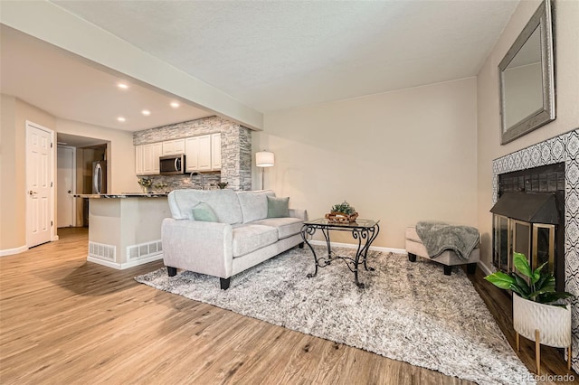 13704 E Lehigh Ave Unit D, Aurora, CO 80014 - living area featuring light wood-type flooring, beam ceiling, recessed lighting, a glass covered fireplace, and baseboards