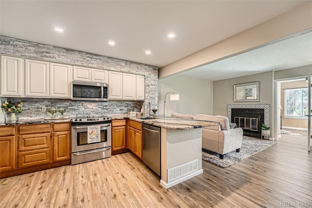 13704 E Lehigh Ave Unit D, Aurora, CO 80014 - kitchen featuring appliances with stainless steel finishes, a peninsula, light wood-type flooring, decorative backsplash, and recessed lighting