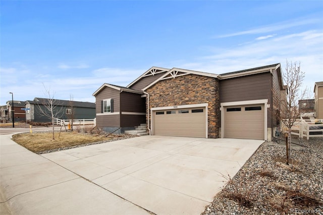 view of front of house with an attached garage, stone siding, and concrete driveway