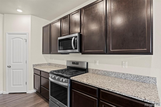 kitchen featuring light stone countertops, dark wood-style floors, appliances with stainless steel finishes, and dark brown cabinets