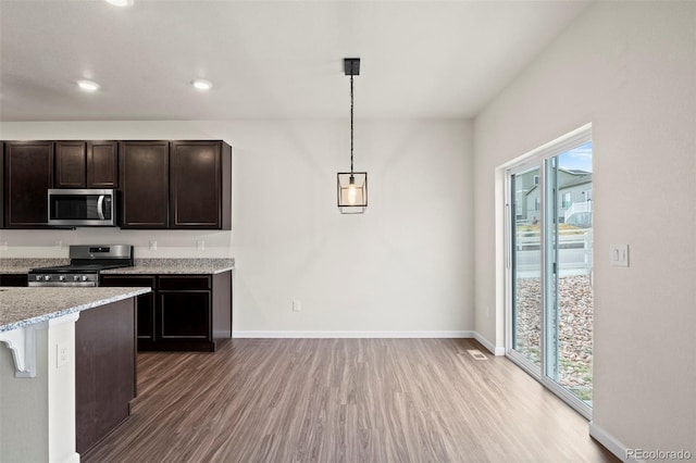 kitchen featuring light wood finished floors, baseboards, appliances with stainless steel finishes, decorative light fixtures, and dark brown cabinets