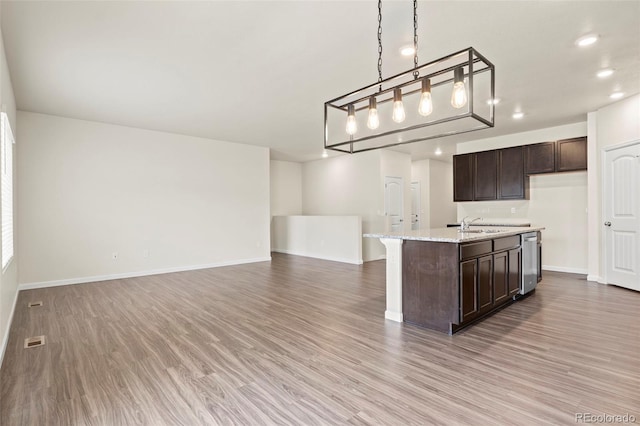 kitchen featuring open floor plan, wood finished floors, dark brown cabinetry, and dishwasher