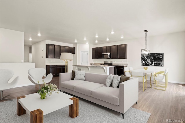 living room with recessed lighting, light wood-style flooring, and baseboards