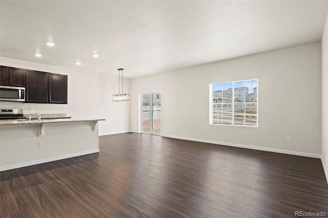 kitchen with stainless steel appliances, a wealth of natural light, dark wood finished floors, and a breakfast bar area