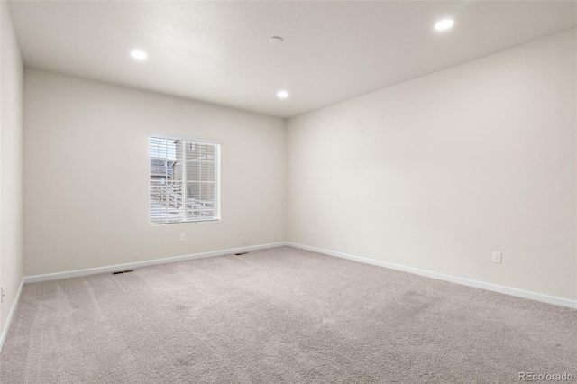 carpeted empty room featuring baseboards, visible vents, and recessed lighting