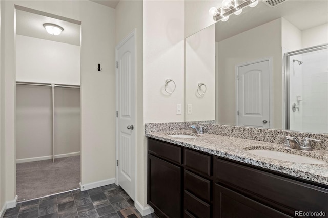 full bathroom featuring double vanity, a sink, a walk in closet, and a shower stall