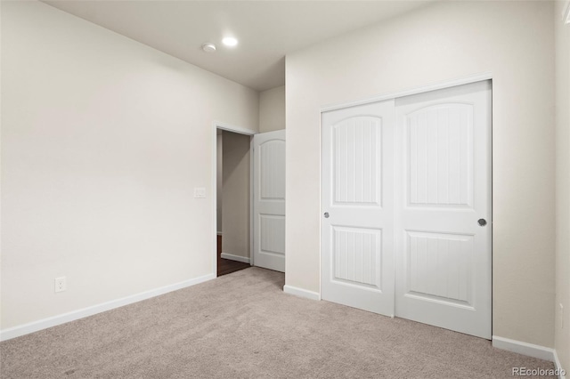 unfurnished bedroom with carpet, a closet, and baseboards