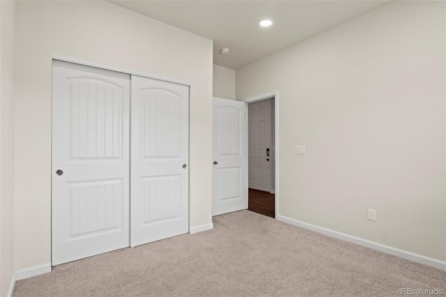 unfurnished bedroom with recessed lighting, a closet, carpet, and baseboards