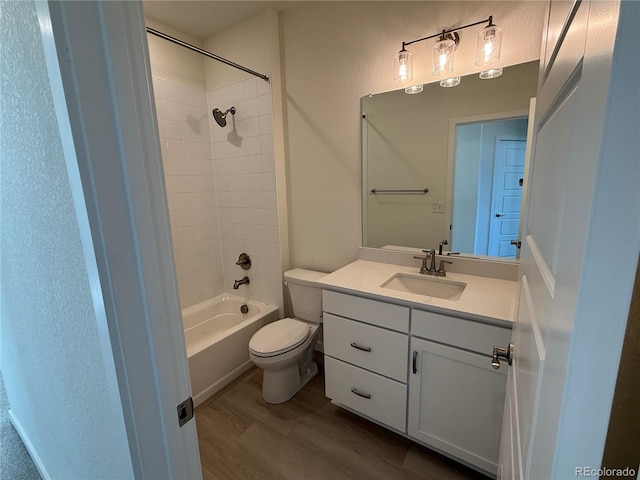 full bathroom featuring wood-type flooring, tiled shower / bath, vanity, and toilet