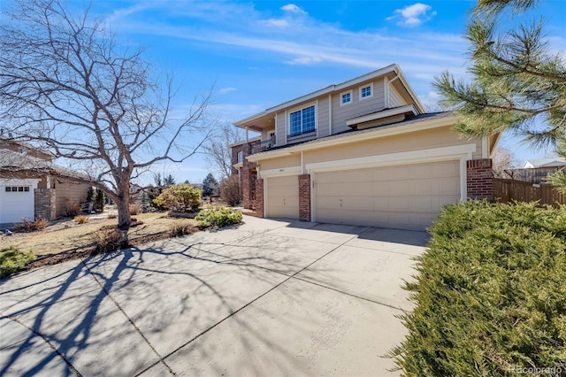 view of front of house with driveway, brick siding, an attached garage, and fence