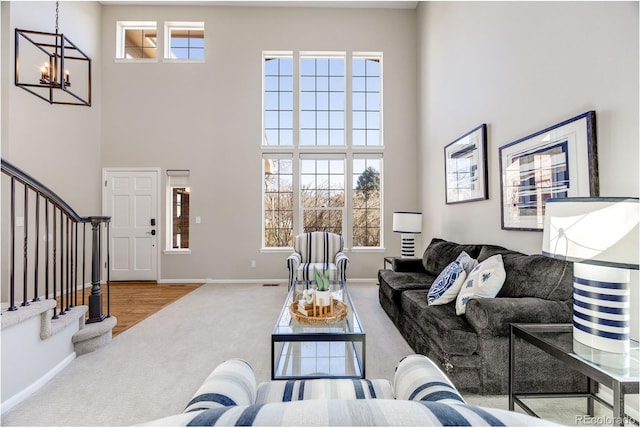 carpeted living room featuring stairway, an inviting chandelier, a towering ceiling, and baseboards