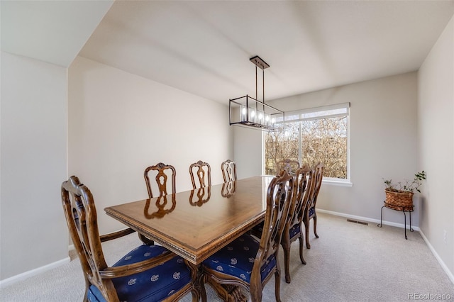 dining room featuring light carpet, visible vents, baseboards, and an inviting chandelier