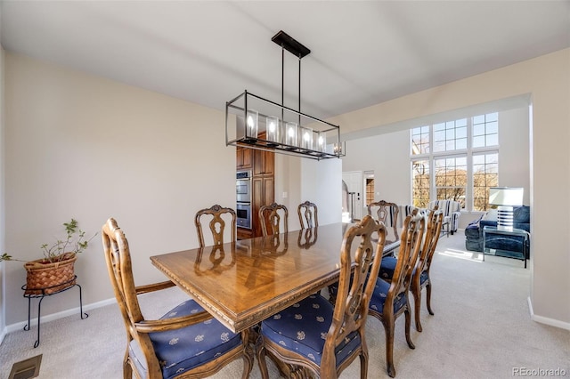 dining room with an inviting chandelier, baseboards, visible vents, and light colored carpet