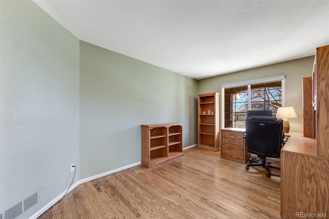 unfurnished office with light wood-style floors, baseboards, and visible vents