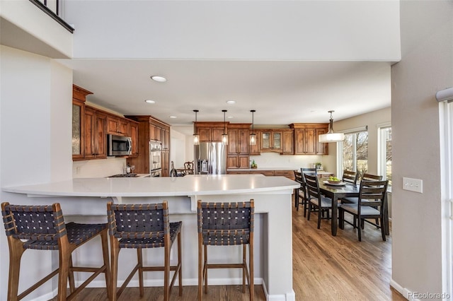 kitchen featuring stainless steel appliances, light countertops, brown cabinets, and a peninsula