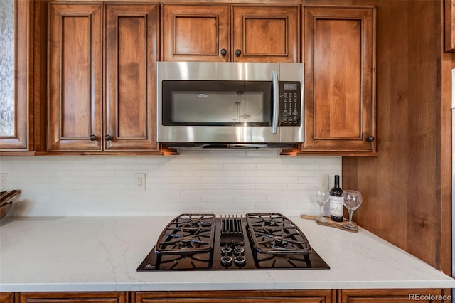 kitchen featuring black gas cooktop, brown cabinets, and stainless steel microwave