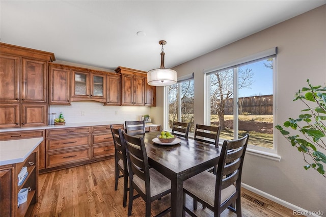 dining space featuring visible vents, light wood-style flooring, and baseboards