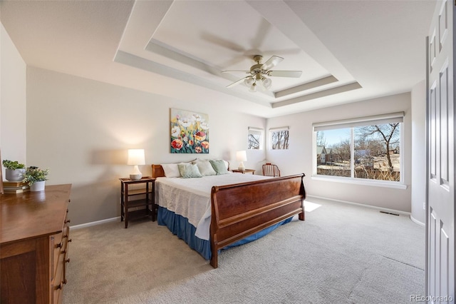 bedroom with light carpet, a ceiling fan, visible vents, baseboards, and a raised ceiling