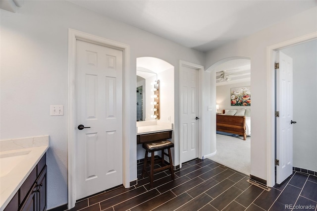 bathroom with ensuite bath, vanity, and baseboards