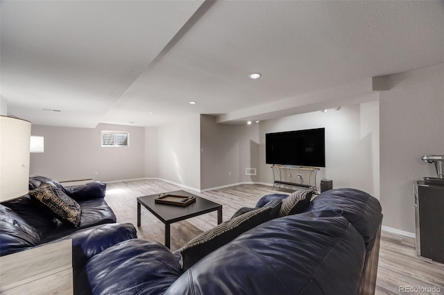 living room with a textured ceiling, recessed lighting, a baseboard heating unit, baseboards, and light wood-style floors