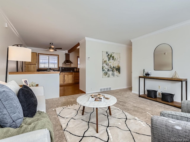 carpeted living room featuring ornamental molding and ceiling fan