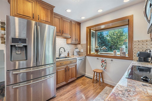 6248 W 75th, Arvada, CO 80003 - kitchen featuring appliances with stainless steel finishes, brown cabinetry, light wood finished floors, tasteful backsplash, and recessed lighting