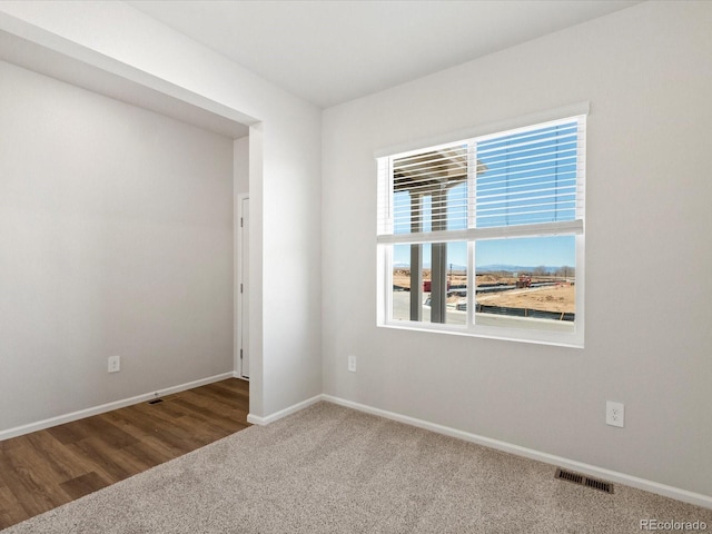 carpeted spare room featuring visible vents and baseboards