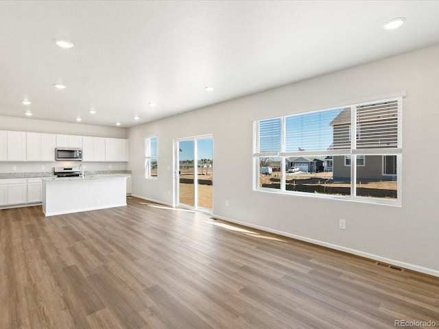 unfurnished living room featuring recessed lighting, wood finished floors, visible vents, and baseboards