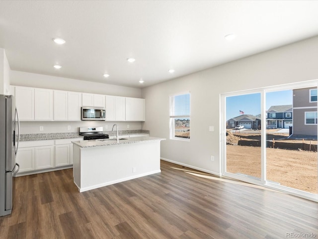 kitchen featuring dark wood finished floors, white cabinets, stainless steel appliances, and light stone countertops