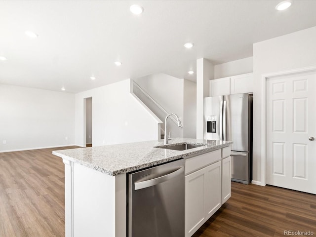 kitchen with a sink, stainless steel appliances, wood finished floors, and a center island with sink