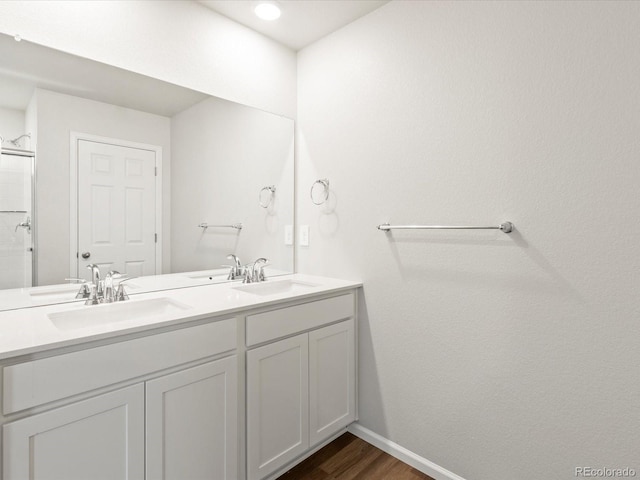 bathroom with double vanity, wood finished floors, baseboards, and a sink