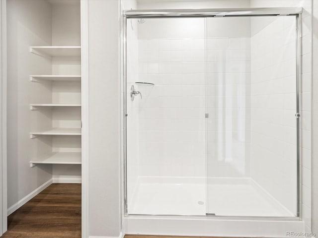 full bathroom with a stall shower, baseboards, and wood finished floors