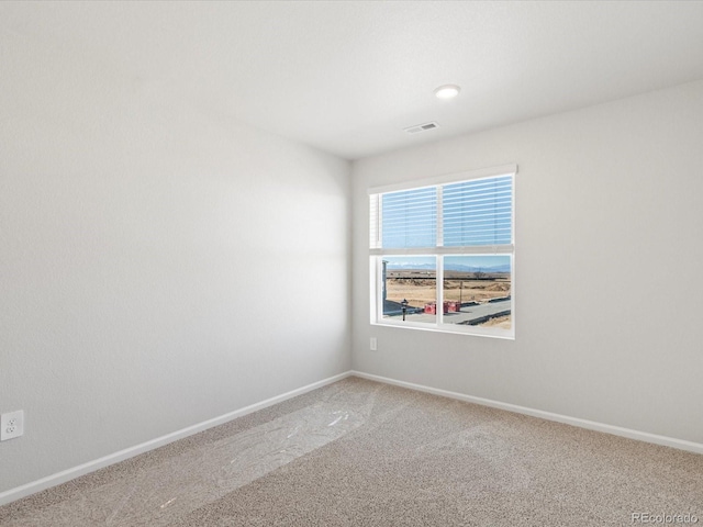 spare room with light colored carpet, visible vents, and baseboards