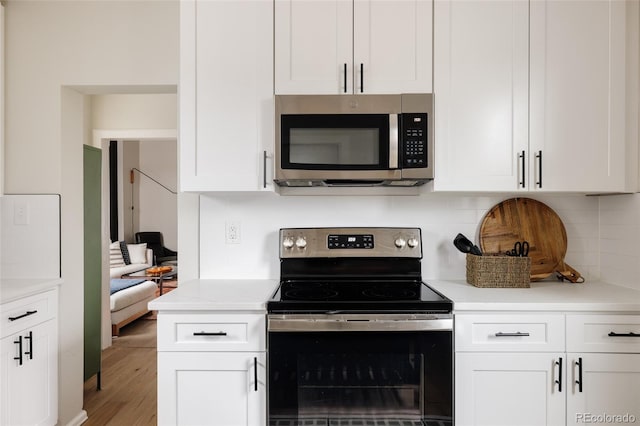 kitchen featuring white cabinets, appliances with stainless steel finishes, backsplash, and hardwood / wood-style floors