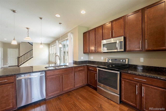 5434 N Xenia St, Denver, CO 80238 - kitchen featuring stainless steel appliances, dark wood-type flooring, a peninsula, hanging light fixtures, and dark stone counters