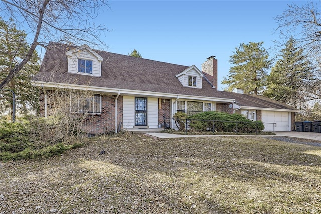 new england style home with concrete driveway, an attached garage, brick siding, and a chimney