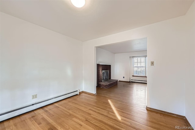 unfurnished living room with a fireplace, light wood finished floors, a baseboard radiator, baseboards, and baseboard heating