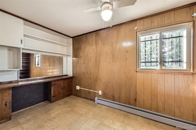 unfurnished office featuring a baseboard radiator, wooden walls, and ceiling fan