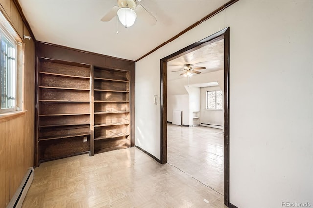 interior space with baseboard heating, wood walls, crown molding, and baseboards